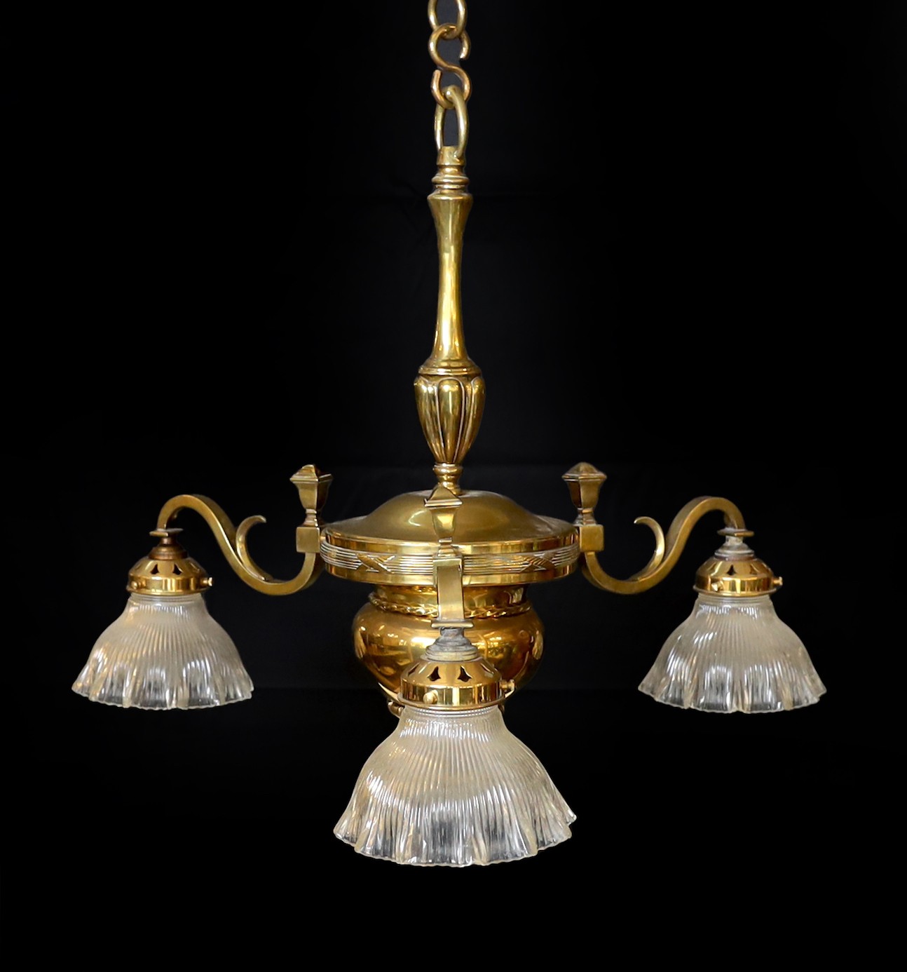 An Edwardian lacquered brass three light chandelier with ribbed glass shades, height 70cm. width 60cm